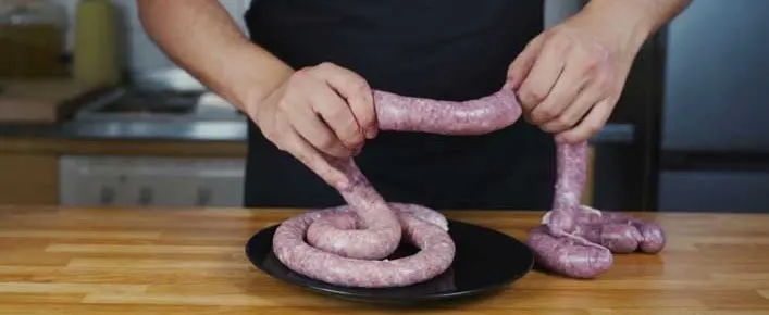 Daniel twisting a freshly filled sausage into links