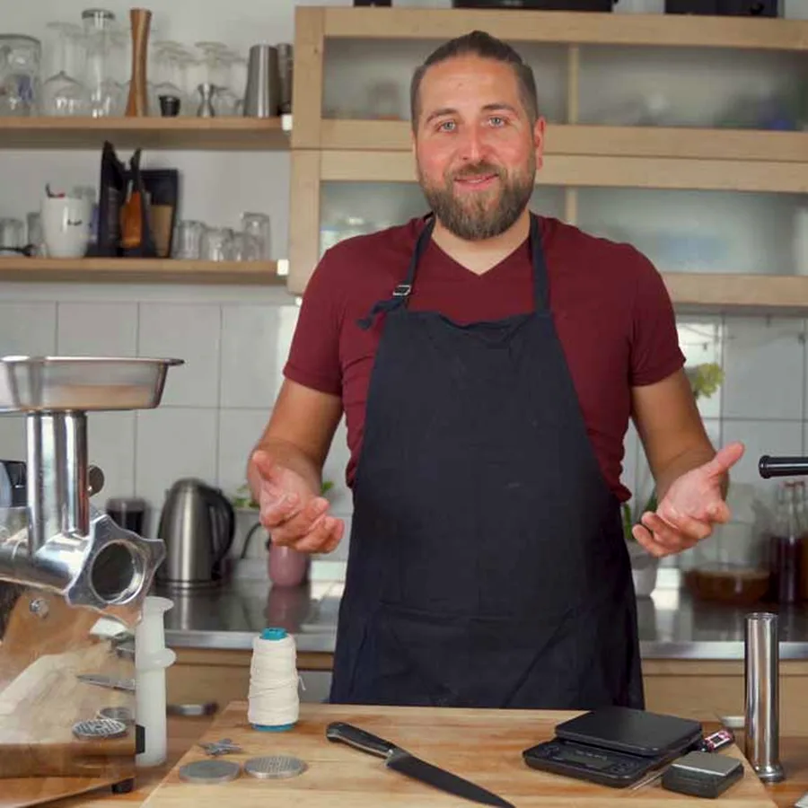 Daniel in his kitchen with a meat grinder, sausage stuffer and scale