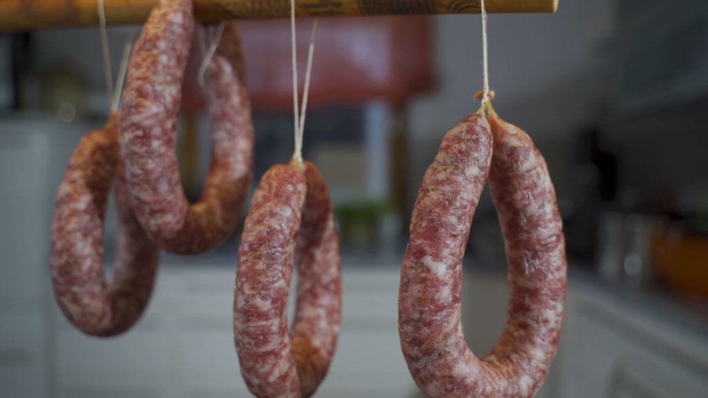 Bregenwurst hanging at room temperature to develop its cured color