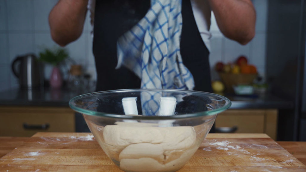 Resting pretzel dough in an oiled bowl