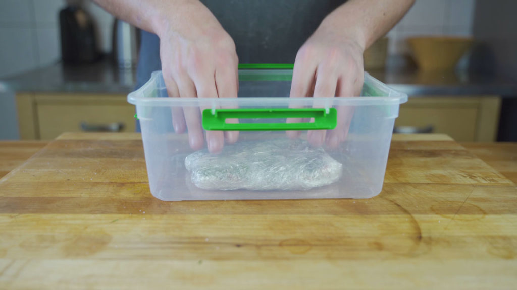 Weighted salmon in a container for curing in the refrigerator