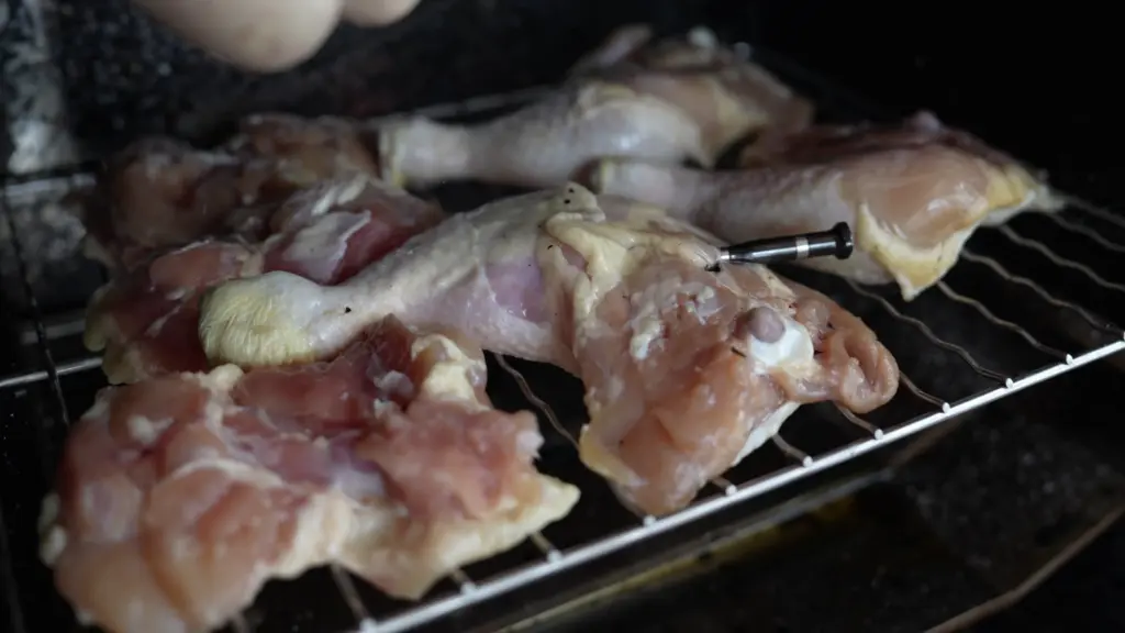 Chicken legs with a meat thermometer drying in the smoker