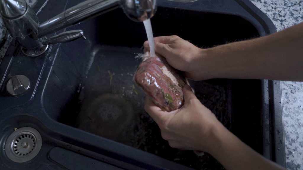 Rinsing cured pork belly under water