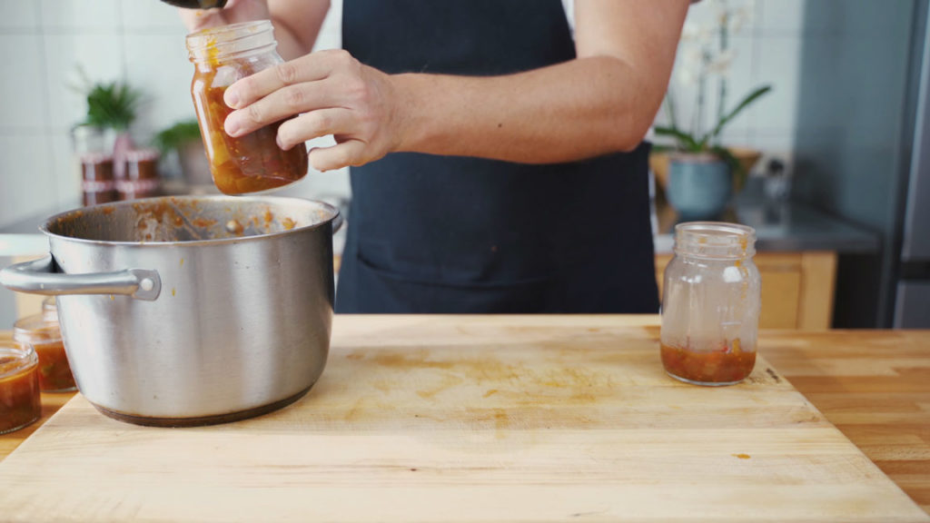 Filling sterilized jars with hot tomato chutney